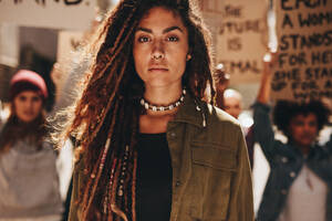 Frau steht im Freien vor Demonstranten auf der Straße; Frau protestiert mit einer Gruppe von Aktivisten im Freien. - JLPSF19038