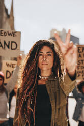 Aktivistin mit Friedenszeichen bei einem Frauenmarsch; Frau führt einen Protest auf der Straße an. - JLPSF19041