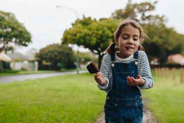 Porträt eines süßen kleinen Mädchens, das im Freien ein Eis isst. Schönes junges Mädchen, das ein Schokoladeneis genießt. - JLPSF19045