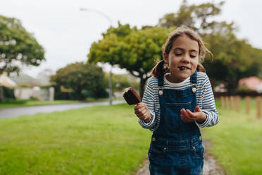 Portrait of cute little girl eating ice cream outdoors. Beautiful young girl enjoying a chocolate candy icecream. - JLPSF19045