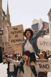 Eine Gruppe aggressiver Demonstranten marschiert mit Schildern auf der Straße. Frauen halten Protestschilder für die Zukunft und die Stärkung der Rolle der Frau. - JLPSF19060