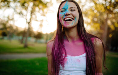 Schöne Frau mit farbigen Pulver auf ihrem Gesicht verschmiert. Lächelnde Mädchen spielen mit Farben während Holi Festival im Park. - JLPSF19283