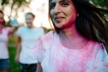 Junge Frau Gesicht mit Farben verschmiert. Mädchen spielt mit Freunden auf der Rückseite während des Festivals der Farben. Spielen Holi mit Freunden. - JLPSF19290