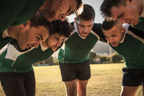 Team of rugby players in huddle discussing their tactics. Professional rugby team in huddle during the game. - JLPSF19308