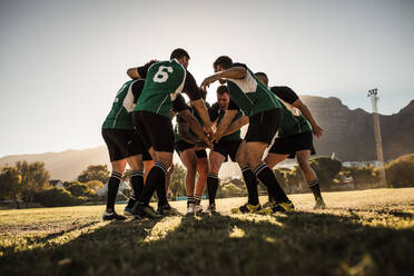 Rugby team putting their hands together after victory. Rugby players cheering and celebrating win. - JLPSF19313