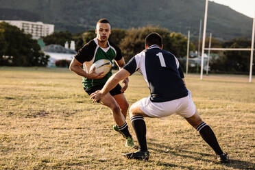 Rugbyspieler, die während des Spiels mit dem Ball rennen und kämpfen. Rugbyspieler, die während des Spiels um den Ball kämpfen. - JLPSF19317