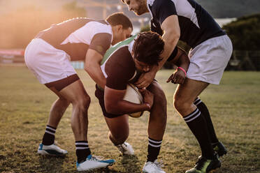 Ein professioneller Rugbyspieler wird von einem Spieler der gegnerischen Mannschaft am Boden blockiert. Rugbyspieler versuchen, während des Spiels an den Ball zu kommen. - JLPSF19318