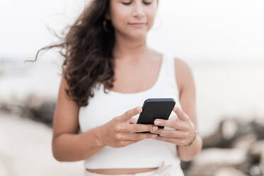 Junge Frau benutzt Smartphone am Strand - MEF00124