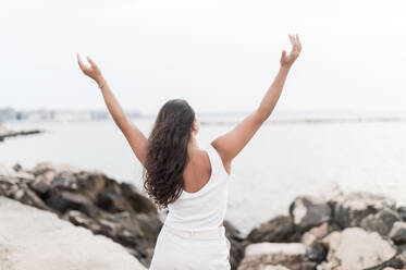 Young woman standing with arms raised at beach - MEF00129