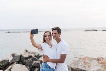 Glückliches Paar nimmt Selfie auf Handy am Strand - MEF00135