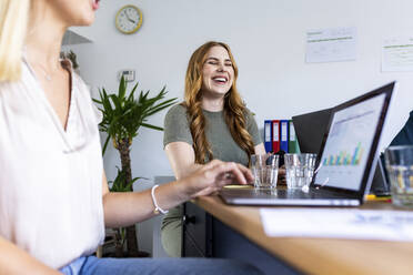 Businesswoman laughing with eyes closed at office - WPEF06645