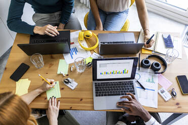 Multiracial colleagues working on desk at office - WPEF06649