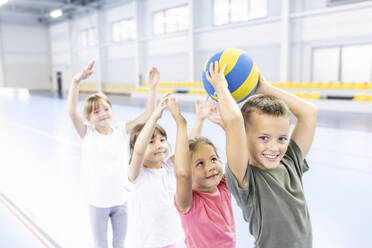 Smiling schoolboy passing ball to friends in line at sports court - WESTF25131