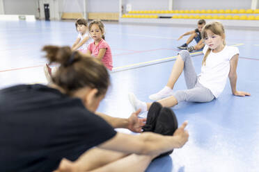 Schüler betrachten den Lehrer bei einer Dehnungsübung auf dem Schulsportplatz - WESTF25140