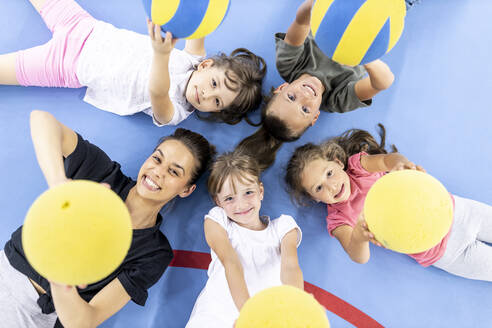 Glückliche Schüler und Lehrer, die sich mit einem Ball auf dem Schulsportplatz hinlegen - WESTF25149