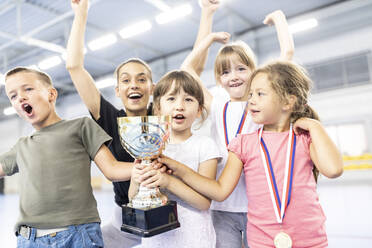 Cheerful students celebrating victory with teacher at school sports court - WESTF25156