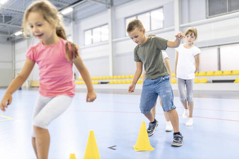 Schüler machen Aufwärmübungen mit Kegeln auf dem Schulsportplatz - WESTF25160