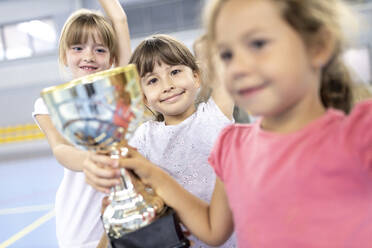 Schülerinnen feiern Sieg mit Pokal auf dem Schulsportplatz - WESTF25166