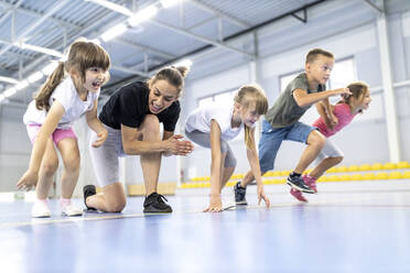 Teacher cheering students at race in school sports court - WESTF25168