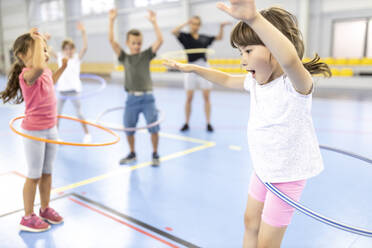 Schüler üben miteinander Hula-Hoop-Reifen auf dem Schulsportplatz - WESTF25172