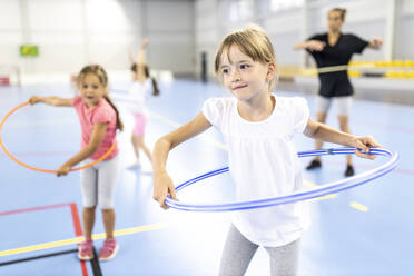 Girl practicing hula hoop at school sports court - WESTF25173