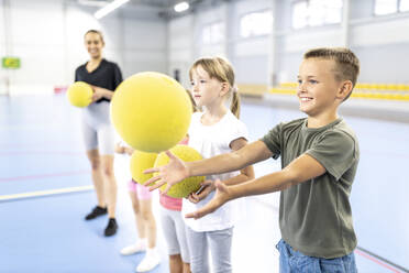 Excited boy catching ball at school sports court - WESTF25176