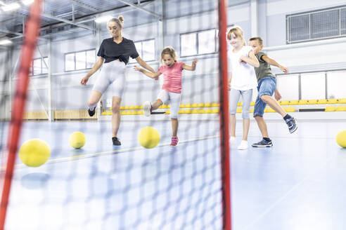 Lehrer und Schüler treten den Ball im Netz auf dem Schulsportplatz - WESTF25181