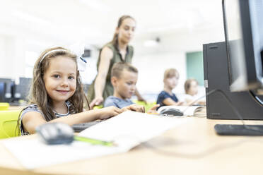 Smiling elementary student sitting in computer class at school - WESTF25192