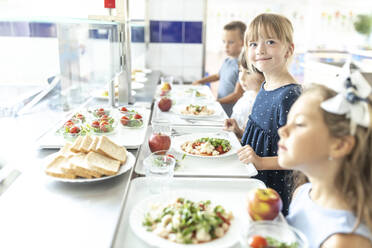 Smiling girl contemplating at lunch break in school cafeteria - WESTF25238