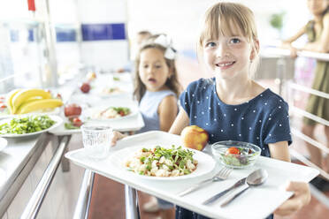 Lächelndes Mädchen mit Tablett in der Mittagspause in der Schulcafeteria - WESTF25239