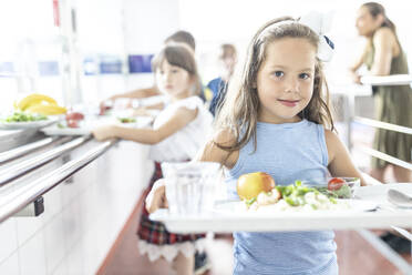 Mädchen mit Mittagessen auf einem Tablett in der Mittagspause in der Schulcafeteria - WESTF25241