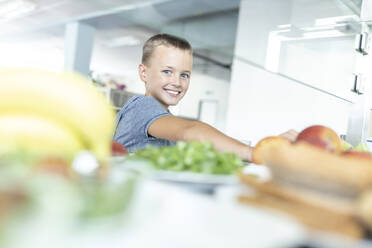 Lächelnder Junge, der in der Cafeteria sein Pausenbrot einnimmt - WESTF25245