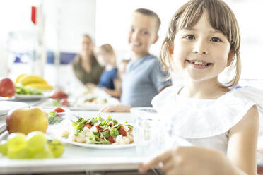 Lächelnde Schülerin mit gesundem Mittagessen in der Schulcafeteria - WESTF25252