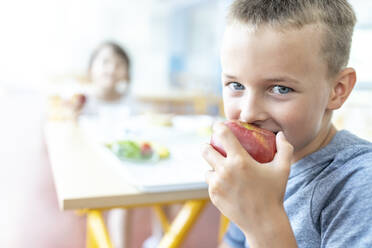 Schuljunge isst frischen Apfel in der Mittagspause in der Cafeteria - WESTF25259