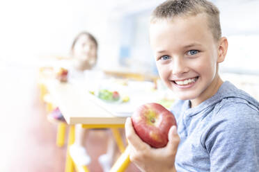 Grundschüler hält Apfel in der Cafeteria - WESTF25260