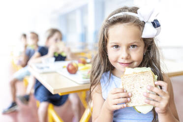 Mädchen mit Stirnband und Sandwich in der Mittagspause in der Cafeteria - WESTF25261