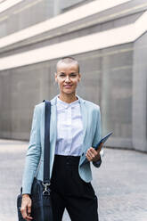 Lächelnde Geschäftsfrau mit Tablet-PC auf dem Fußweg stehend - OIPF02512