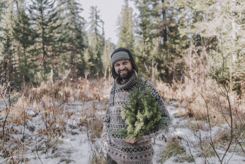 Lächelnder reifer Mann in warmer Kleidung im Wald - VBUF00219