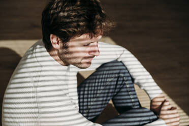 Thoughtful businessman with shadow of window blinds on him in office - EBBF06724