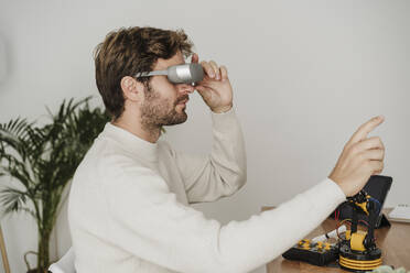 Engineer gesturing with VR goggles in modern office - EBBF06737