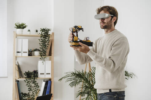 Ingenieur beobachtet Roboterarm durch VR-Brille im Büro - EBBF06755