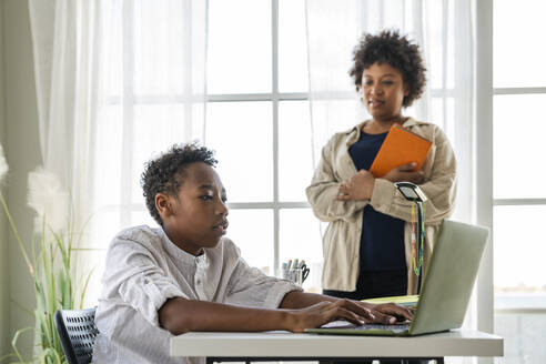 Junge lernt zu Hause mit dem Laptop seiner Mutter - VPIF07633