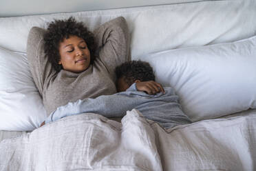 Mother and son sleeping on bed at home - VPIF07664