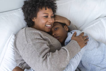 Happy mother cuddling son in bed at home - VPIF07677