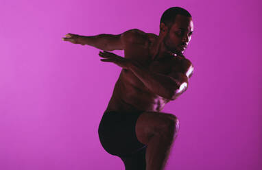 Focussed sportsman doing fitness workout. Monochrome fitness portrait of athletic man working out on purple background. - JLPSF19415