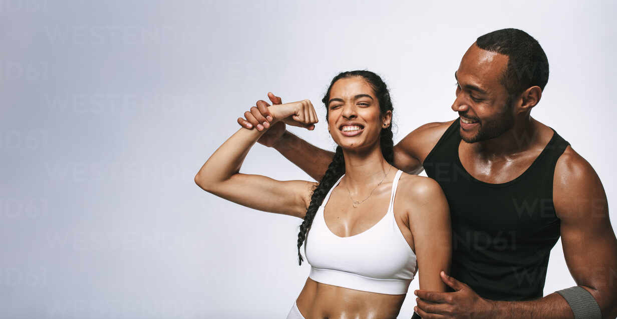 https://us.images.westend61.de/0001747689pw/cheerful-fitness-woman-having-fun-showing-biceps-standing-with-male-athlete-fitness-couple-sharing-happy-moments-after-workout-JLPSF19432.jpg