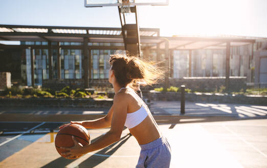 Junge Frau spielt Streetball an einem Sommertag. Streetballspielerin in Aktion. - JLPSF19457