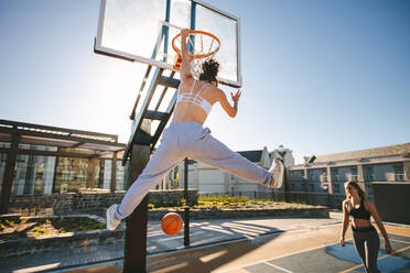 Frauen spielen Basketball auf der Straße. Frau Streetball-Spieler macht Slam Dunk in einem Basketball-Spiel. - JLPSF19461