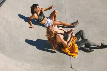 Mädchen sitzen an der Skate-Schüssel und lachen. Frauen Freunde entspannen im Freien auf Skate-Park. - JLPSF19471