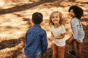 Schönes Mädchen mit Freunden in einem Park, eine Gruppe von Kindern spielt im Wald. - JLPSF19513